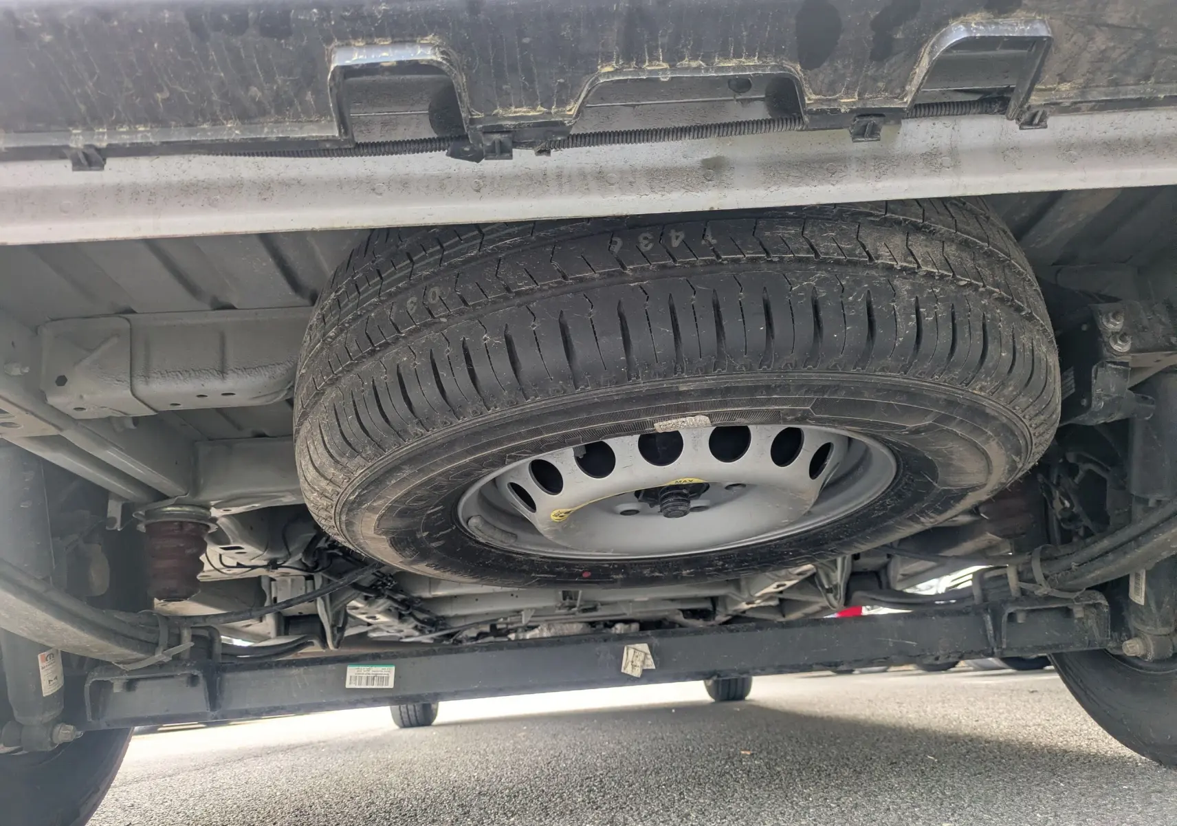 Vue en contre-plongée sous un FIAT Ducato Fourgon blanc, montrant la roue de secours fixée sous le châssis.