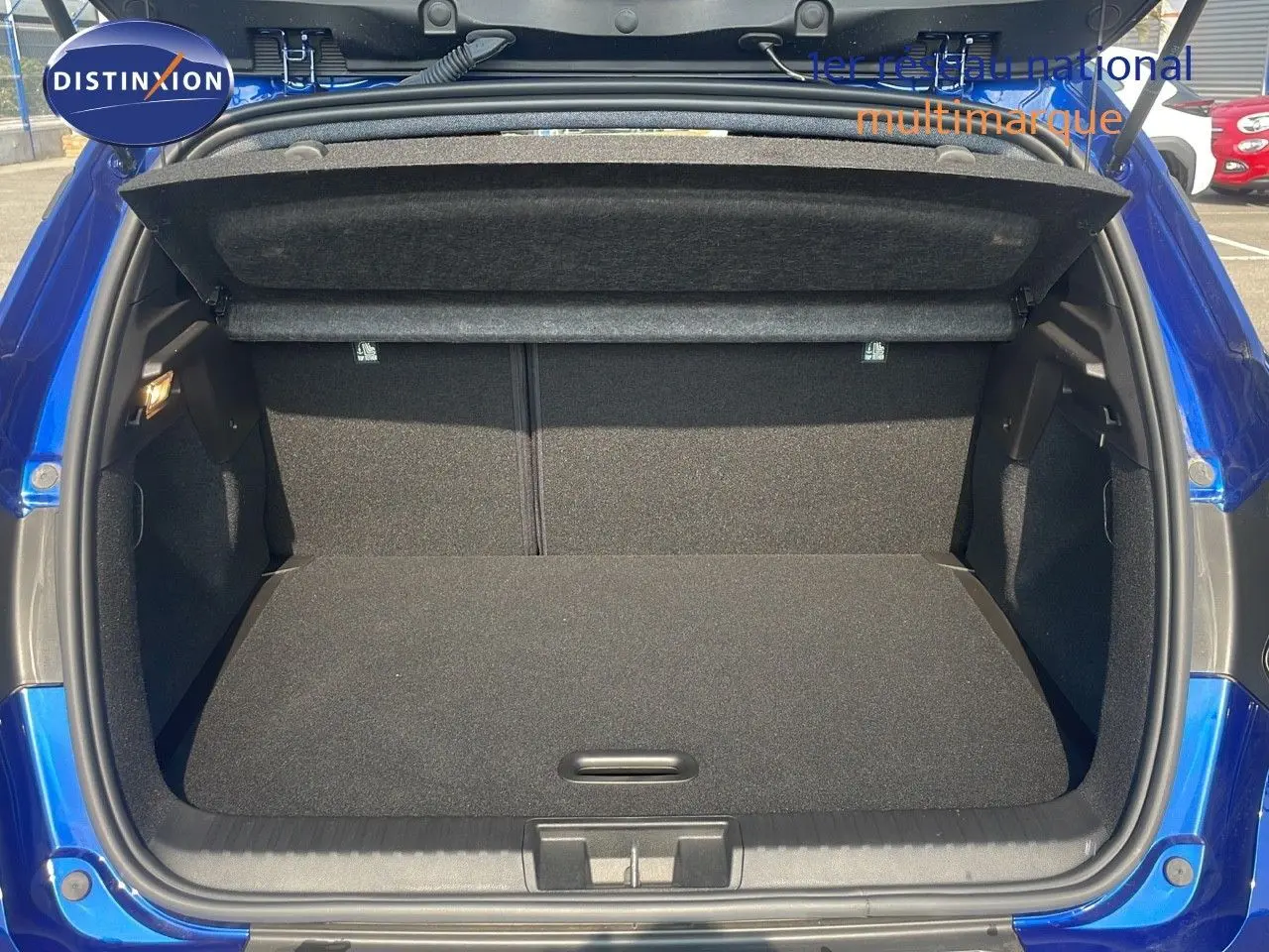 Coffre ouvert d'un Renault Captur bleu Iron Metal, vue arrière montrant l'espace de chargement vide et la plage arrière.