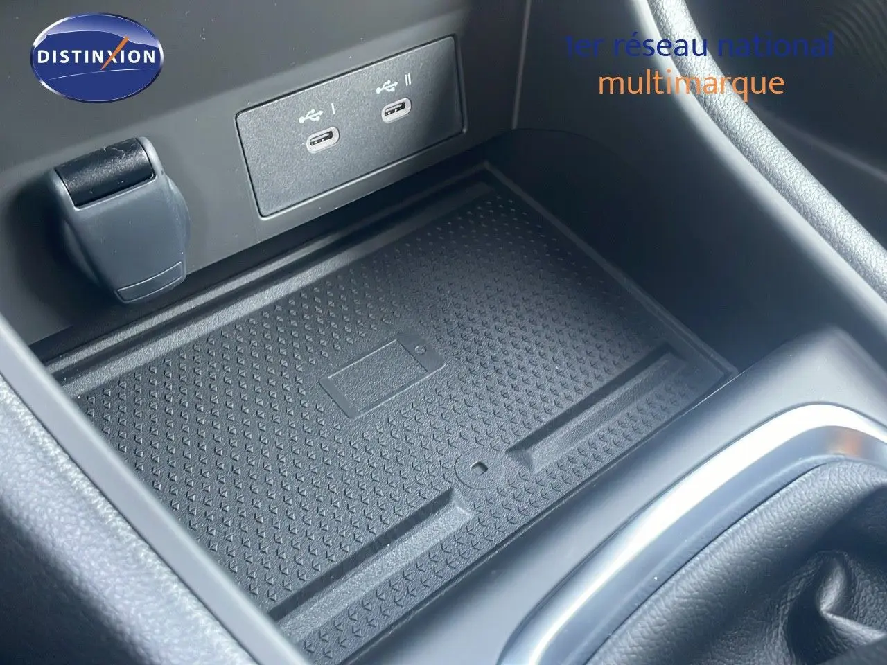 Gros plan sur la console centrale du Renault Captur 2025 montrant un espace de rangement avec ports USB et prise 12V.