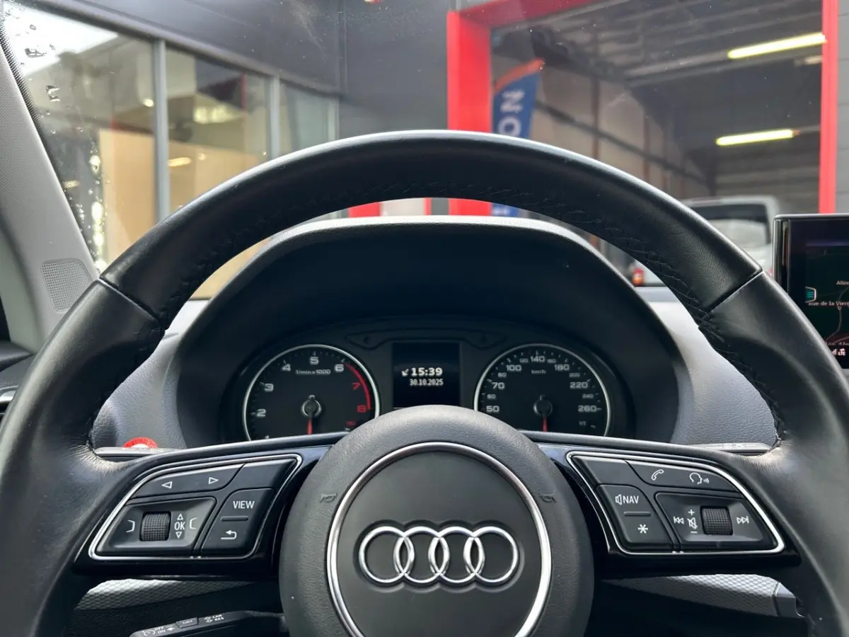 Vue centrée du volant cuir Audi Q2 noir 2023 avec combiné d'instruments et commandes multifonctions visibles.