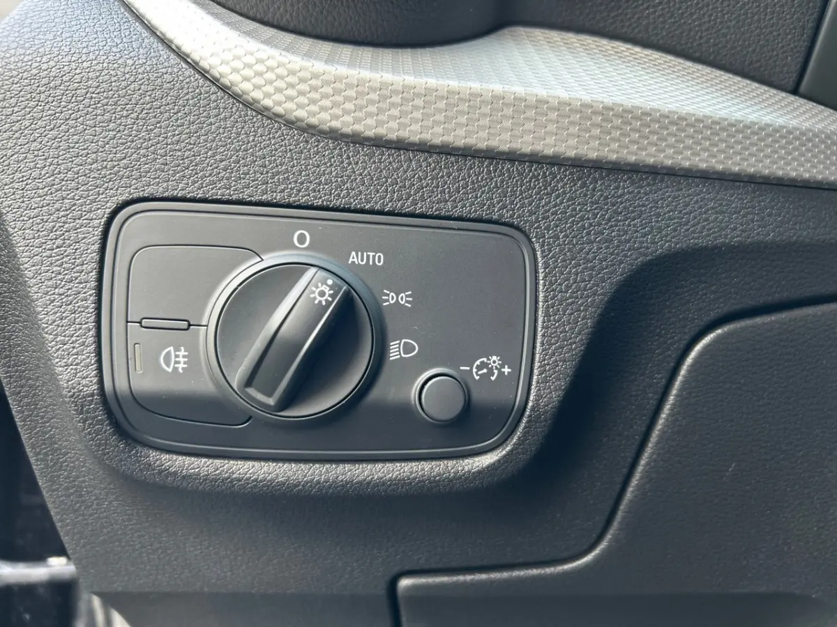 Gros plan sur le bouton de commande des phares noir dans l'habitacle de l'Audi Q2 35 TFSI S Line 2023.