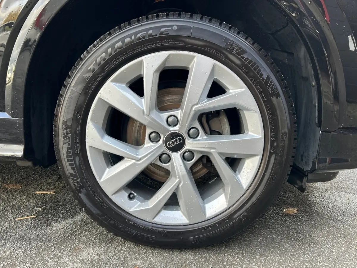 Gros plan sur la roue avant droite argentée d'un Audi Q2 noir 2023 avec jante en alliage et pneu Triangle.