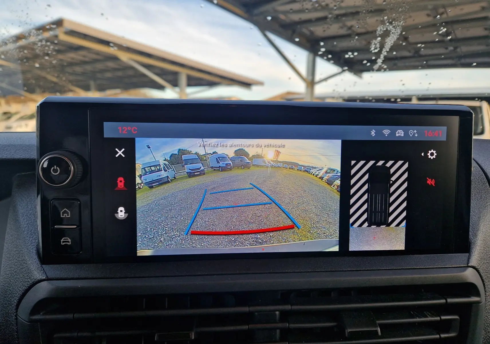 Écran de caméra de recul du FIAT Scudo Fourgon blanc 2024 affichant vue arrière avec lignes de guidage et parking gravillonné.