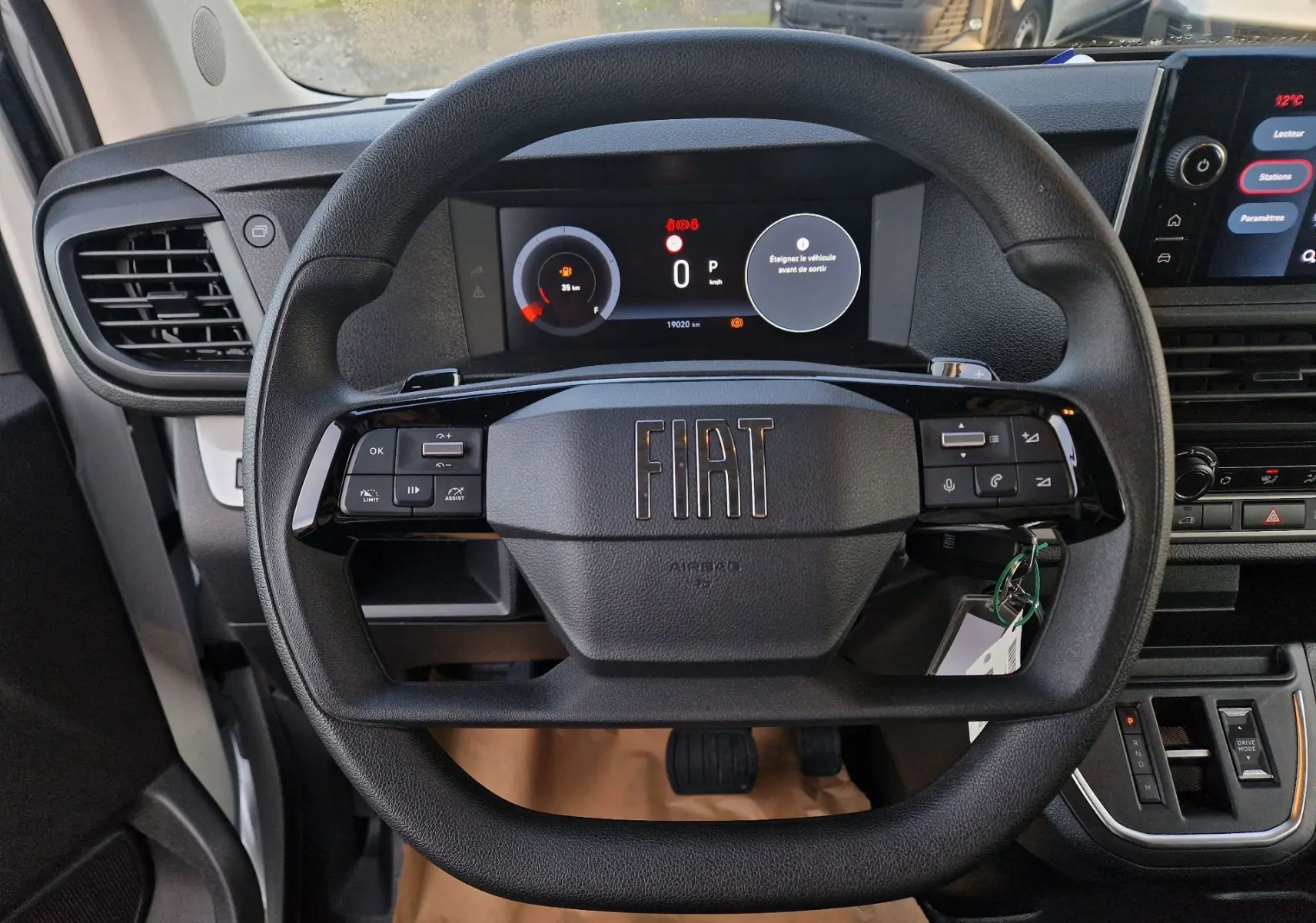 Vue rapprochée du volant noir du Fiat Scudo Fourgon 2024 avec tableau de bord digital et commandes intégrées.