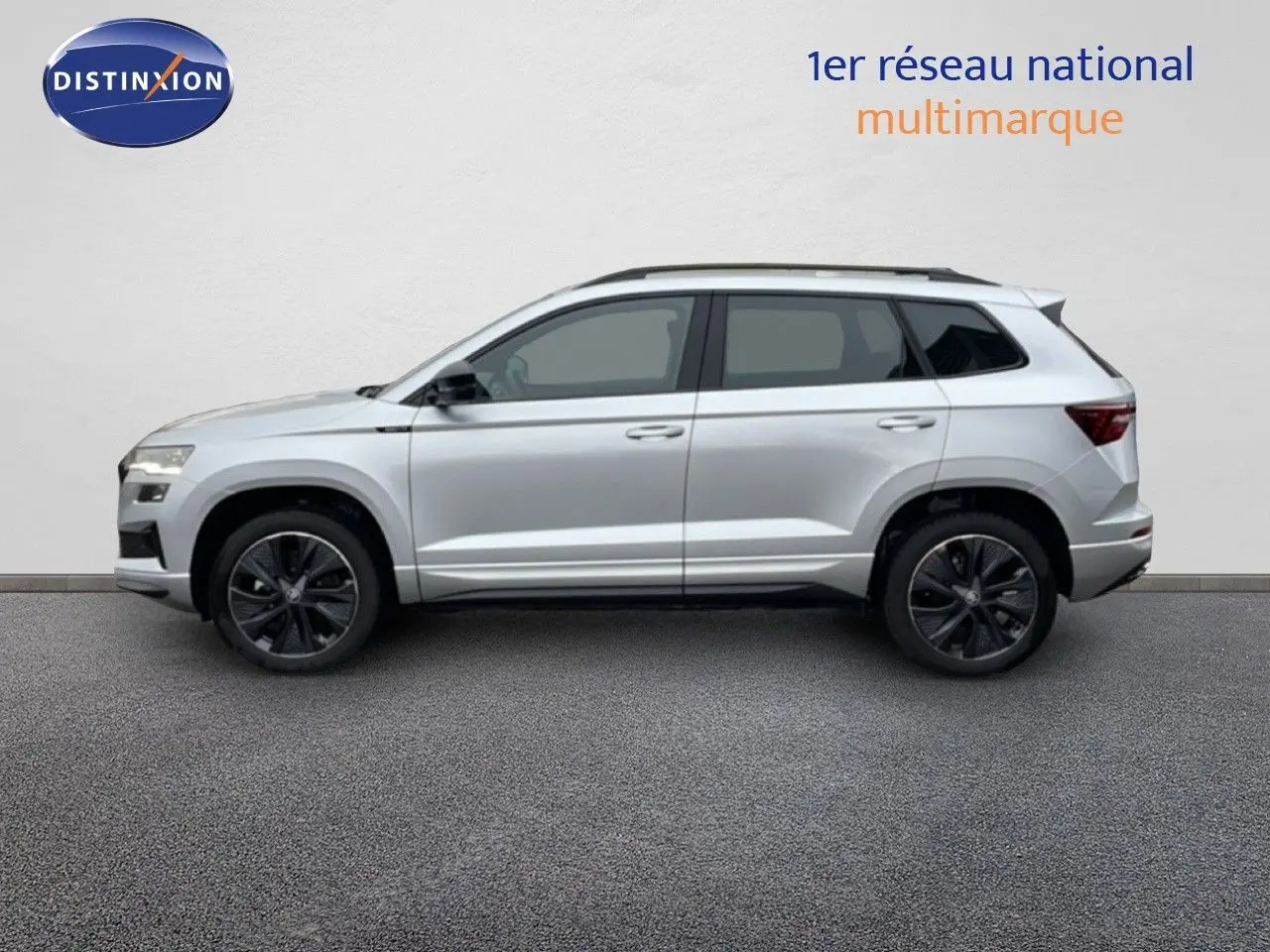 Vue de profil côté gauche d'un Skoda Karoq gris argent métallisé avec jantes noires et toit ouvrant.