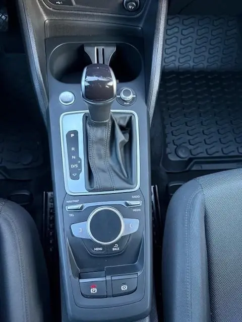 Vue rapprochée de la console centrale noire de l'Audi Q2 35 TFSI 150 S Tronic S Line avec levier de vitesse automatique et molette de contrôle.