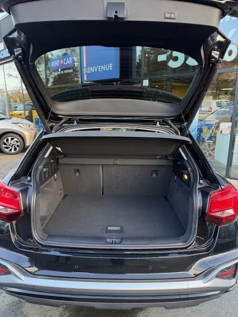 Coffre ouvert vu de l’arrière d’un Audi Q2 noir 2023, montrant l’espace de chargement et la tablette de séparation.