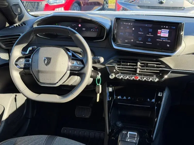 Vue intérieure avant centrée sur le volant et l'écran tactile du tableau de bord du Peugeot 2008 gris 2024.