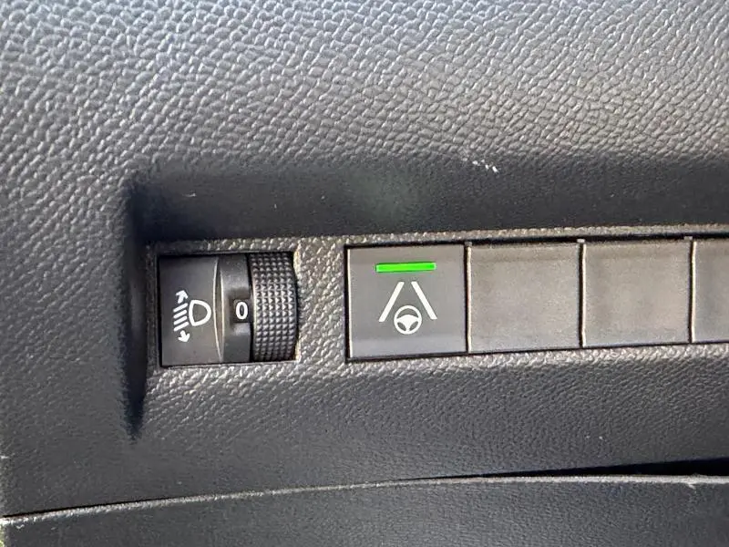 Bouton de réglage des phares et activation du maintien de voie sur tableau de bord noir d'une Peugeot 2008 gris Selenium.