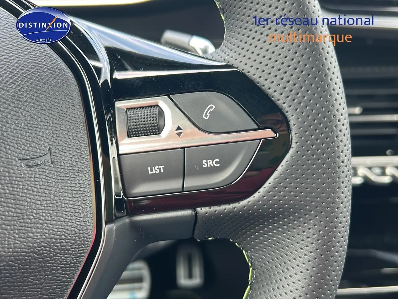 Gros plan sur les commandes gauche du volant cuir perforé du Peugeot 2008 noir hybride 2025.