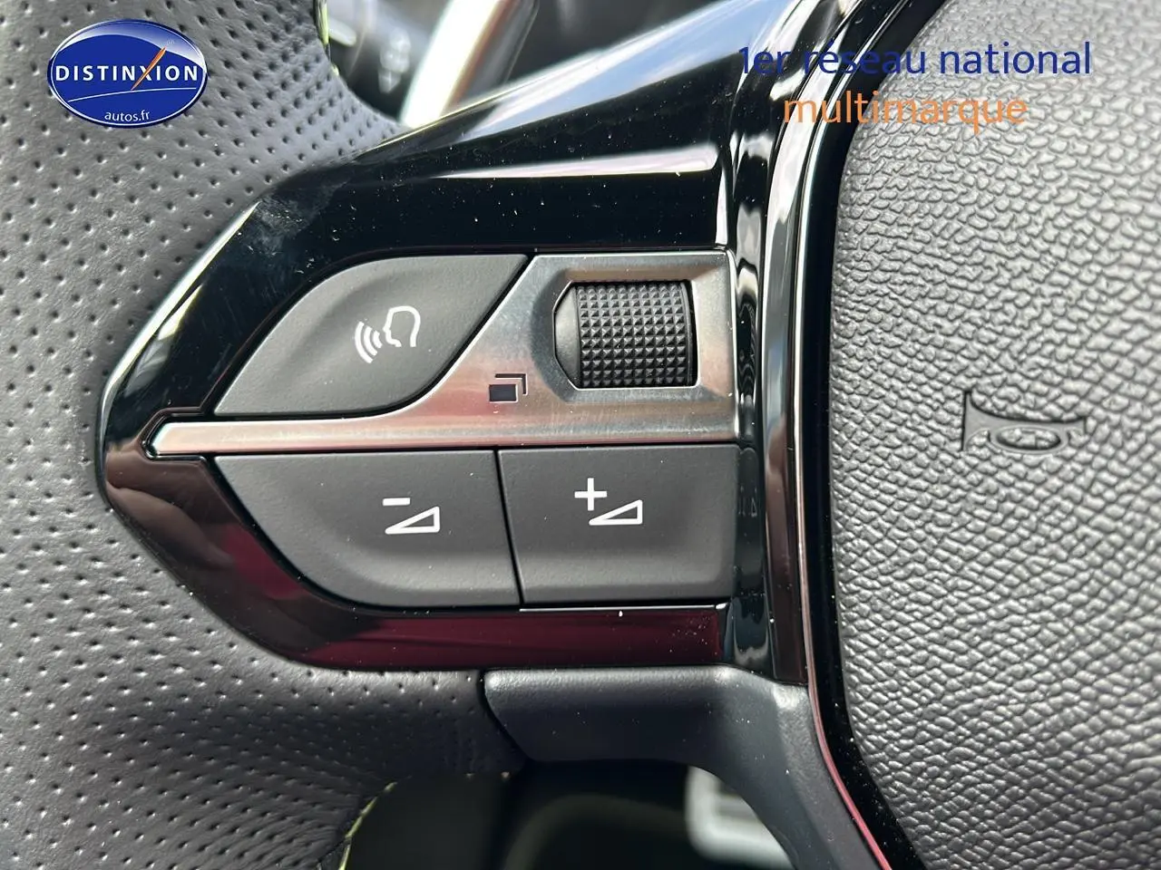 Gros plan sur les commandes gauche du volant cuir noir perforé du Peugeot 2008 1.2 hybrid 145 GT 2025.