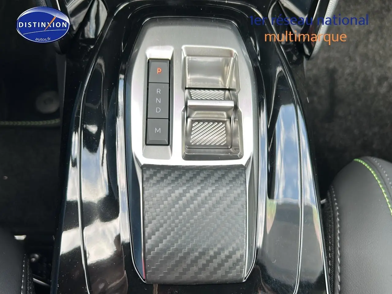Vue rapprochée de la console centrale noire avec sélecteur de vitesses et finition carbone dans une Peugeot 2008 1.2 hybrid 145 GT.