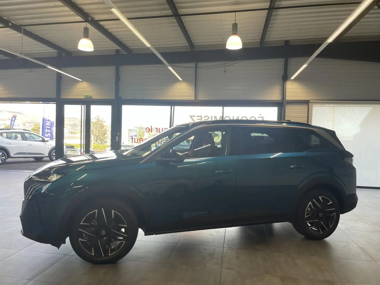 Peugeot 5008 Bleu Obsession vue de profil côté gauche en intérieur avec jantes alliage noires et toit noir.