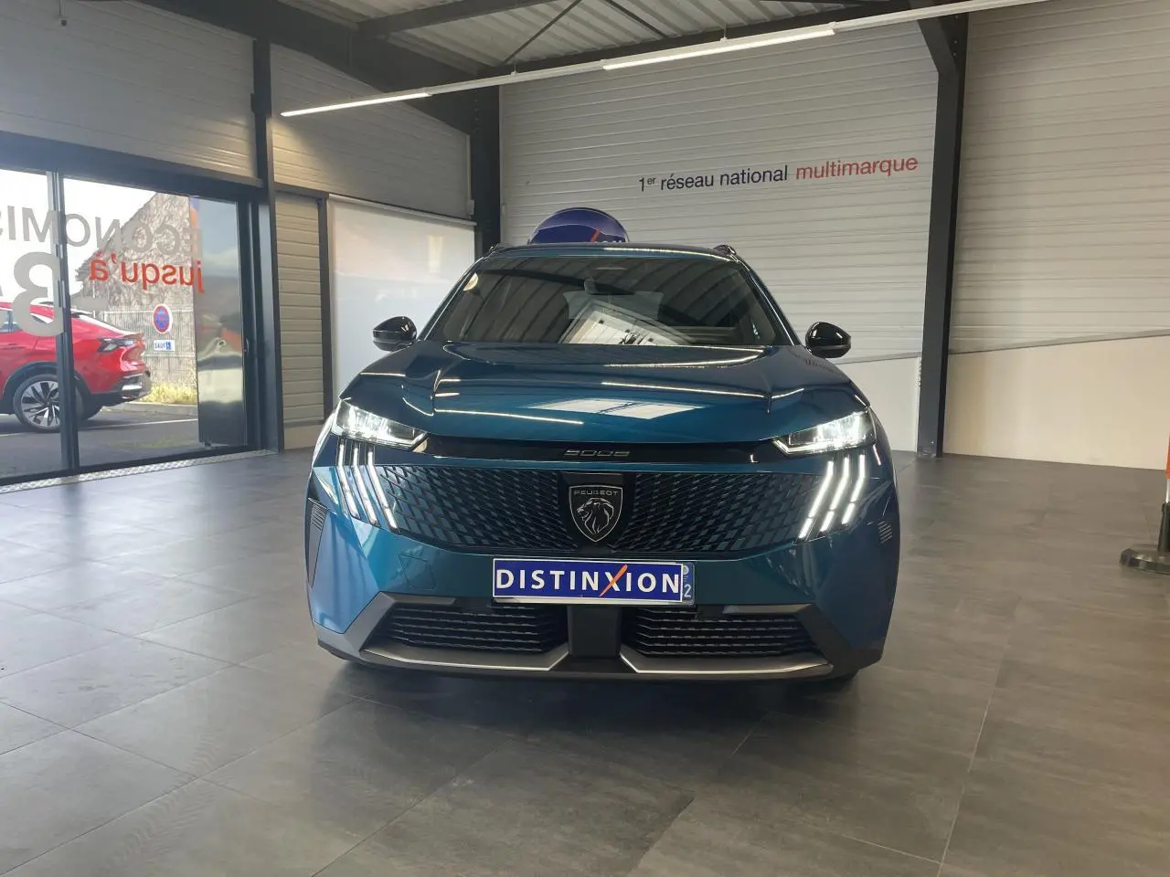 Vue avant frontale du Peugeot 5008 bleu Obsession avec calandre noire et feux LED à griffes distinctifs.