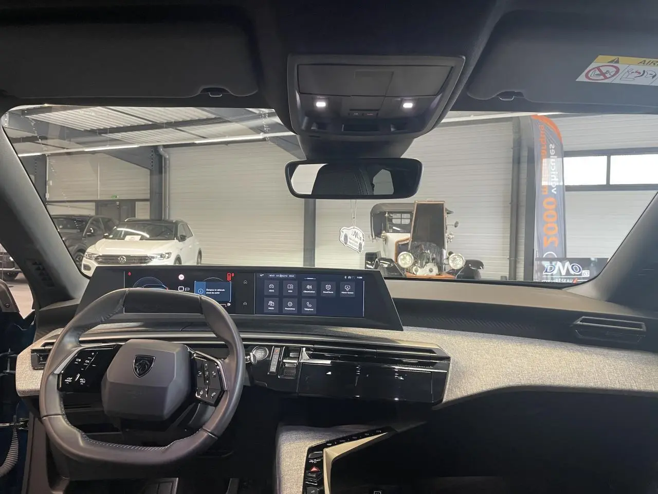 Vue intérieure avant du Peugeot 5008 2025 Bleu Obsession, tableau de bord avec double écran HD et volant compact cuir.