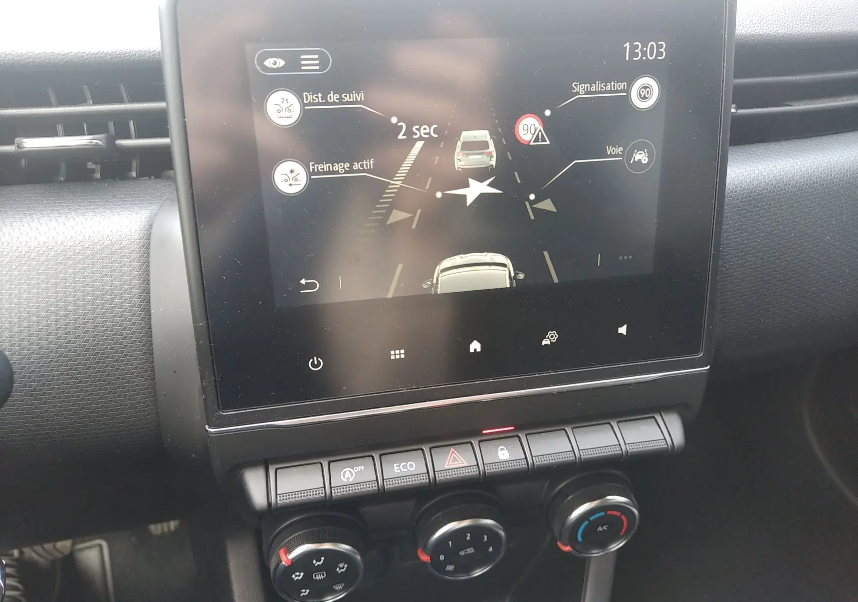 Écran tactile central de la Renault Clio V 2023 montrant l'assistance à la conduite avec commandes climatisation en dessous.