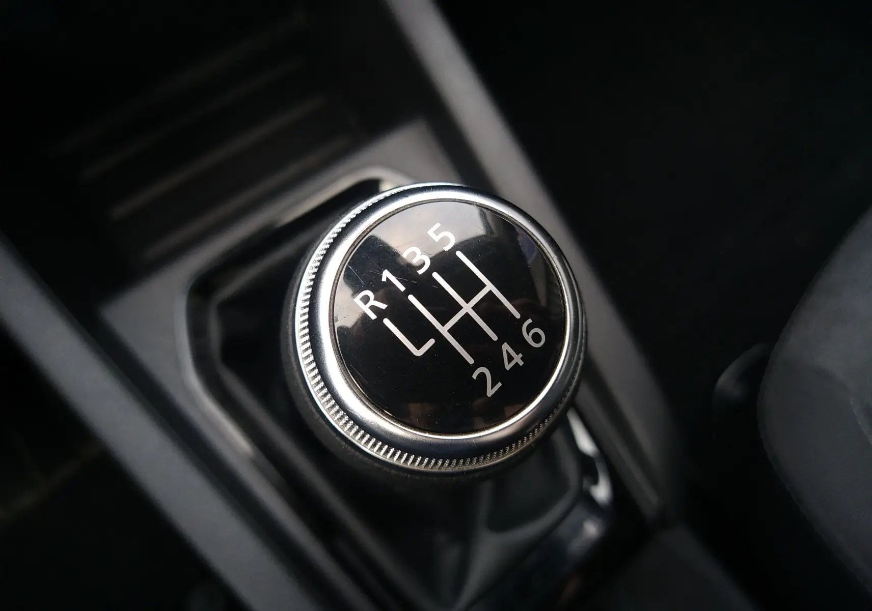 Gros plan sur le levier de vitesses manuel noir de la Renault Clio V 1.0 TCE 90ch, intérieur sombre.