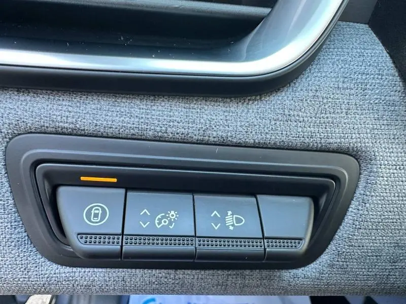 Gros plan sur les commandes de réglage de luminosité et phares sur tissu gris à l'intérieur d'une Renault Clio Gris Rafale.