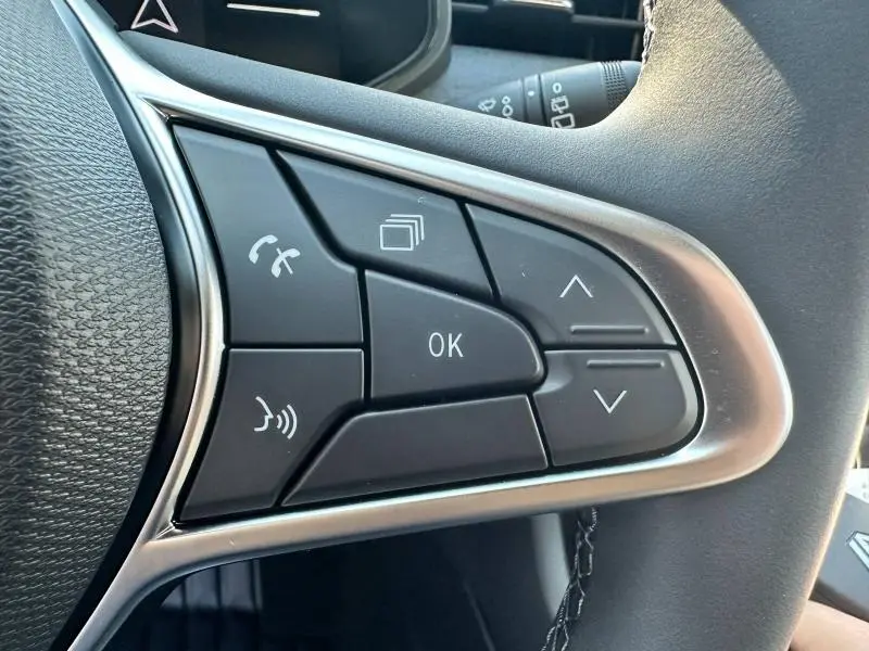 Gros plan sur les commandes multifonctions noires du volant de la Renault Clio 2025, finition Gris Rafale.