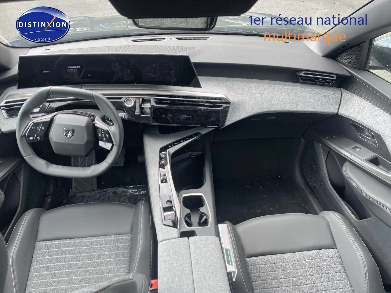 Vue intérieure avant du Peugeot 5008 Hybrid 145 Allure 2025, soulignant le volant cuir multifonction et la console centrale grise.