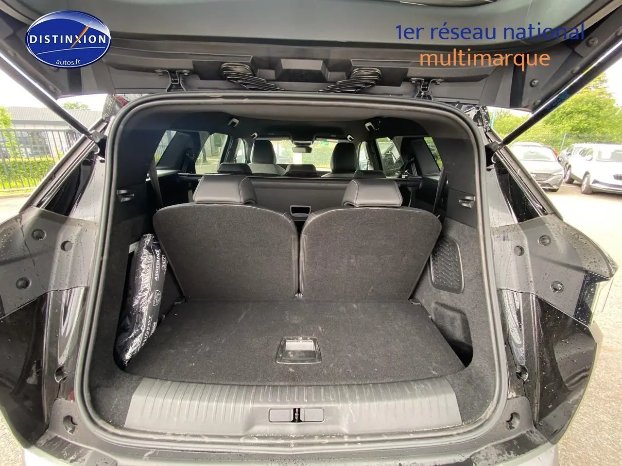 Coffre ouvert vu de l'arrière d'un Peugeot 5008 noir, montrant les sièges arrière partiellement relevés et l'habitacle.
