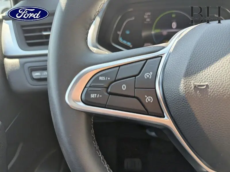 Gros plan sur les commandes au volant à gauche du Renault Captur gris Cassiopée, avec boutons de régulateur de vitesse visibles.