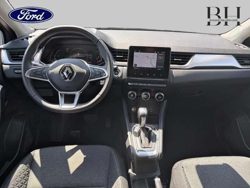 Vue intérieure avant du Renault Captur gris Cassiopée avec tableau de bord moderne et écran tactile central.