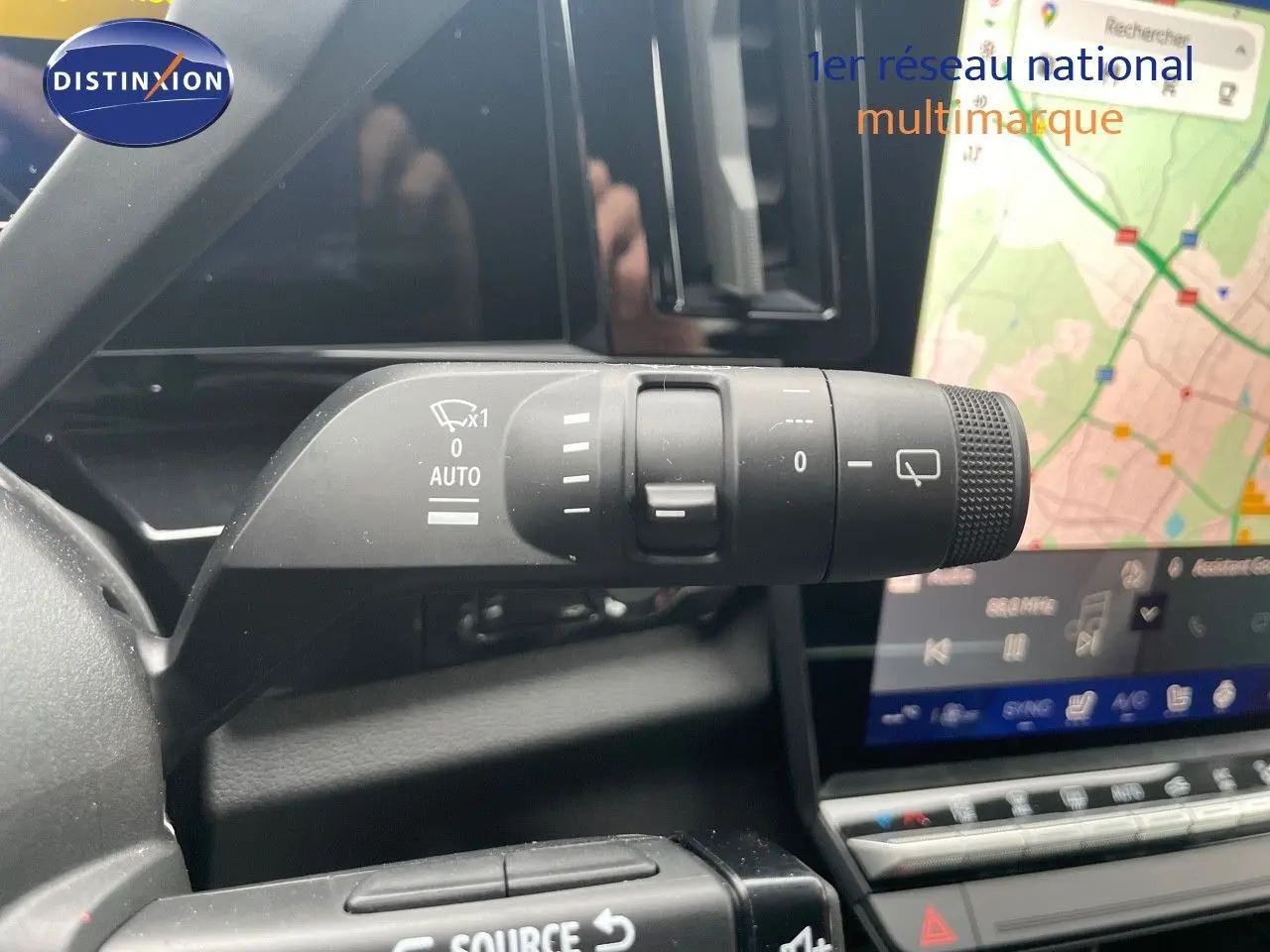 Gros plan sur la commande d’essuie-glace du Renault Austral gris métal 2025, avec écran tactile et carte GPS en arrière-plan.
