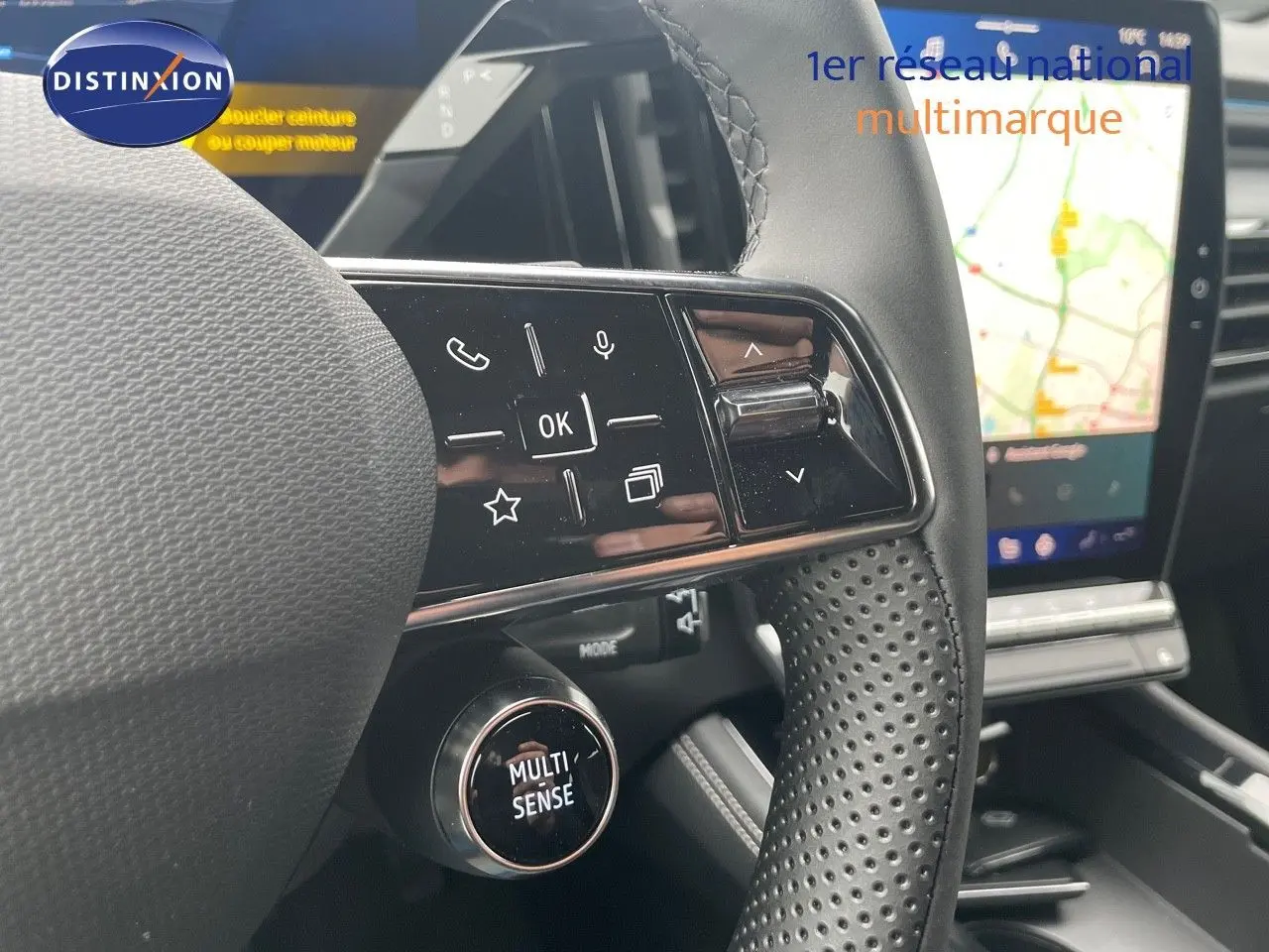 Gros plan sur le volant perforé et les commandes multifonctions du Renault Austral 1.2 E-Tech gris métal, avec écran tactile en arrière-plan.