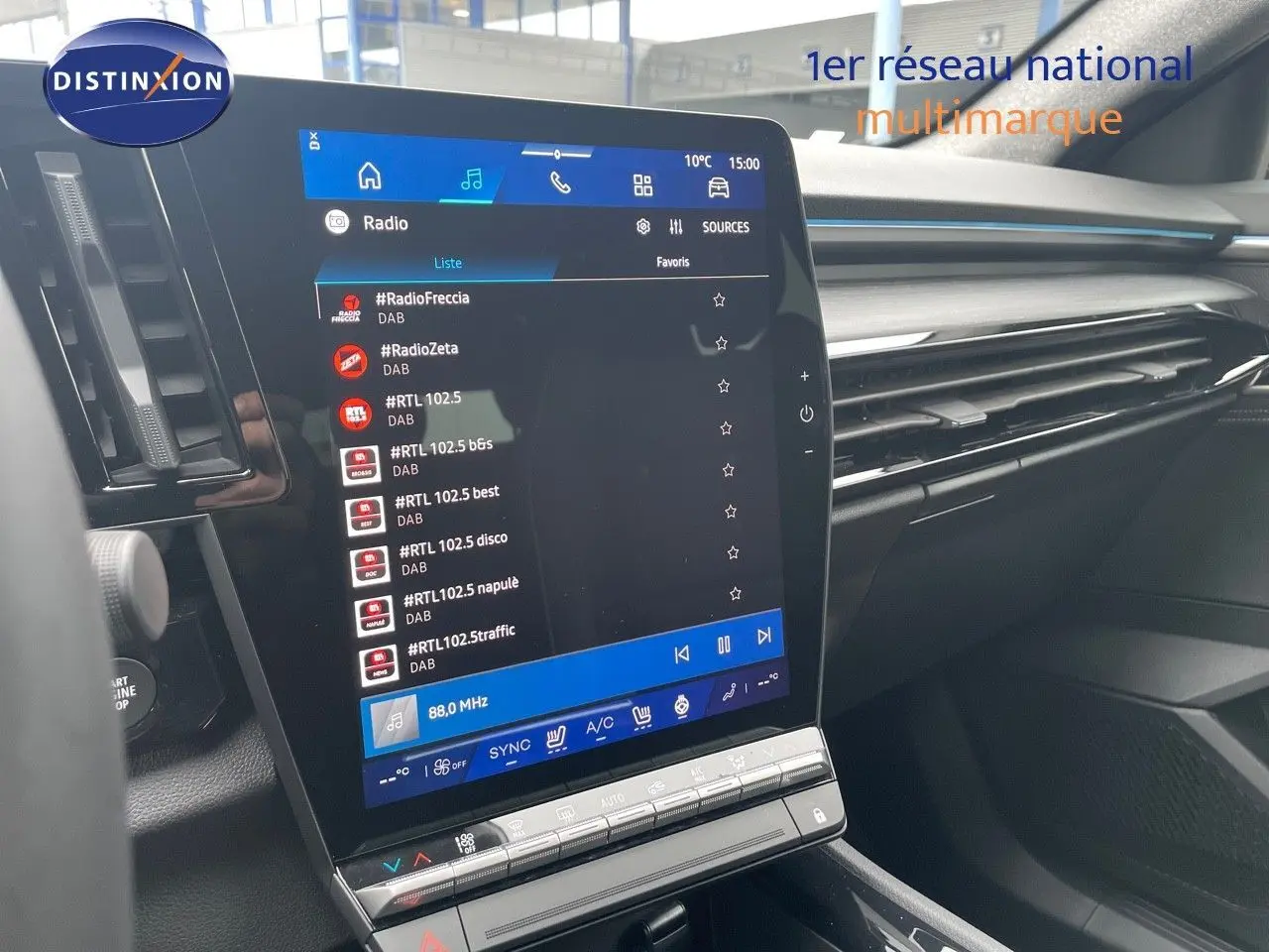 Vue intérieure centrée sur l’écran tactile du tableau de bord du Renault Austral gris métal 2025, affichant la radio DAB.