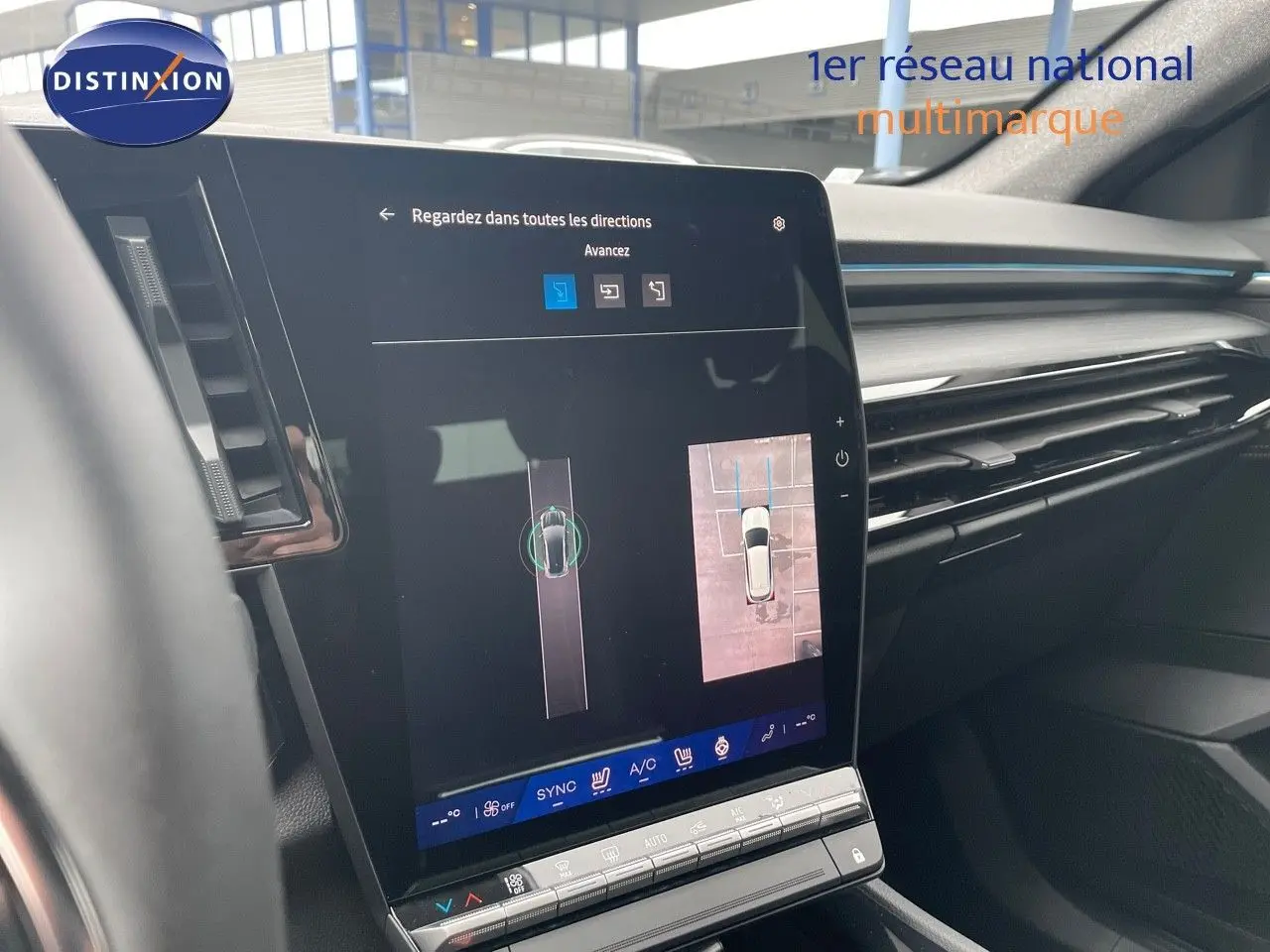 Vue intérieure du tableau de bord du Renault Austral 2025 gris métal, avec écran tactile affichant la caméra de recul et l’aide au stationnement.