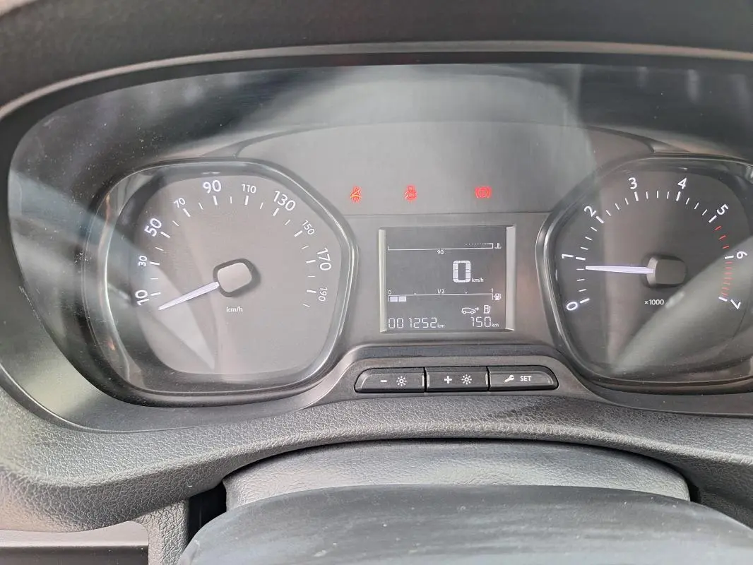 Vue rapprochée du tableau de bord noir de l'Opel Vivaro blanc, affichant compteur et écran digital.