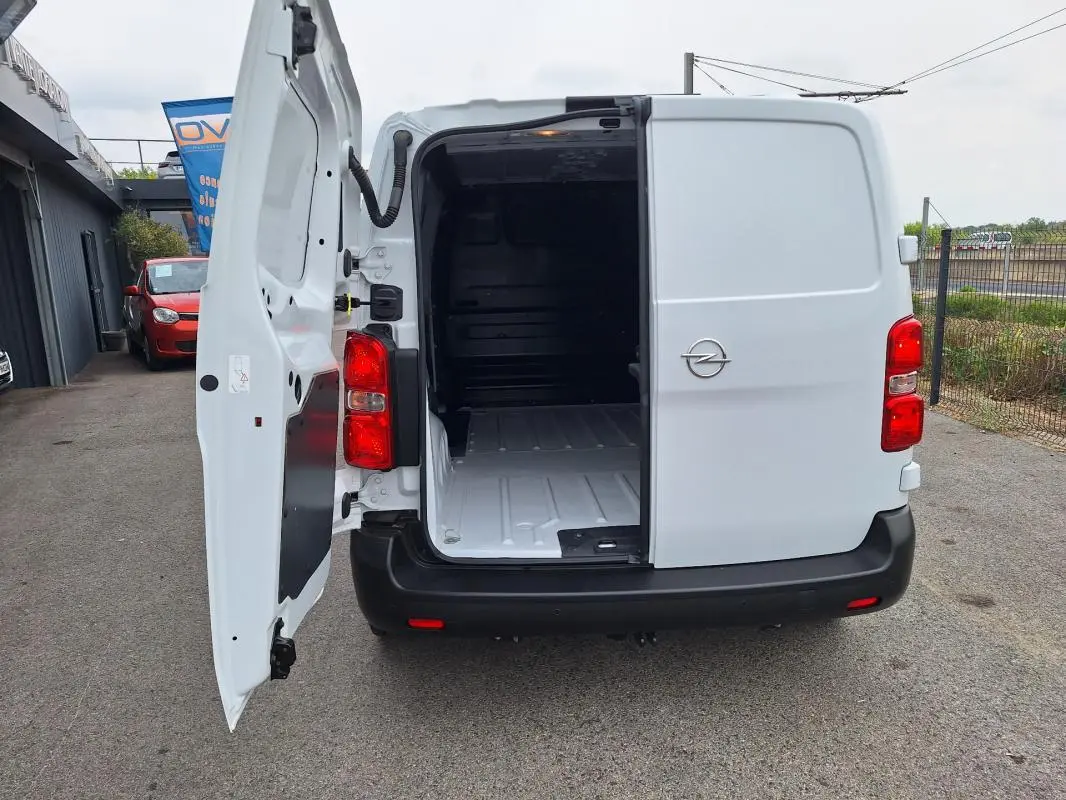Vue arrière d’un Opel Vivaro blanc 2025 avec porte latérale gauche ouverte, montrant l’espace de chargement vide.