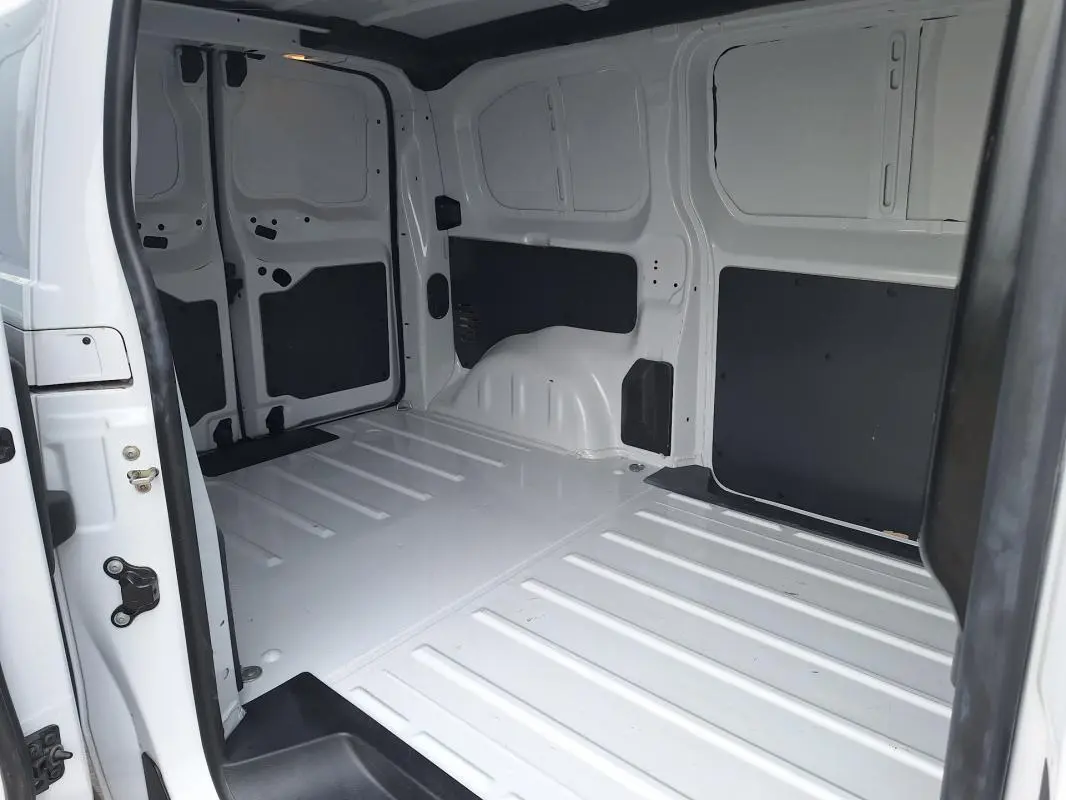 Vue intérieure du fourgon Opel Vivaro blanc, montrant l’espace de chargement vide avec porte latérale ouverte.