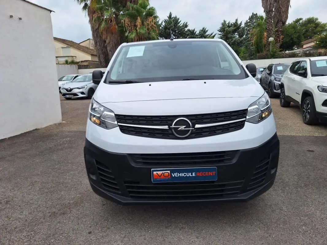 Vue frontale d’un Opel Vivaro blanc avec calandre noire et plaque « Véhicule récent » visible.