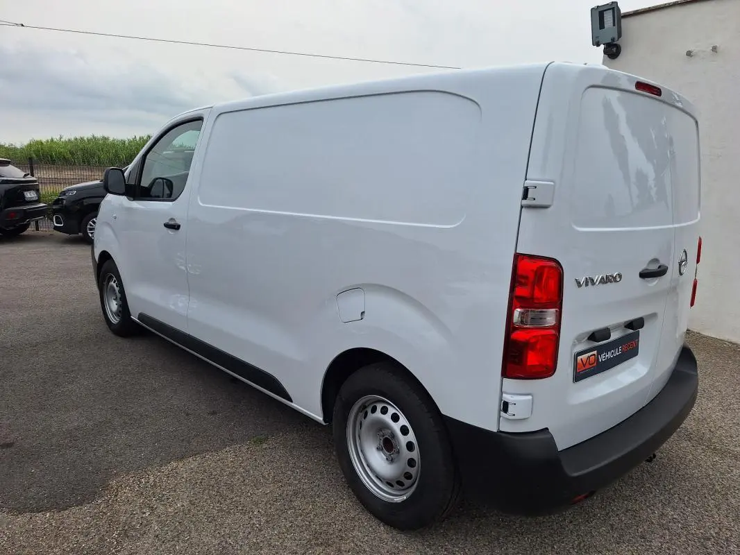 Vue 3/4 arrière droite d'un fourgon Opel Vivaro blanc, avec porte latérale et feux arrière rouges visibles.