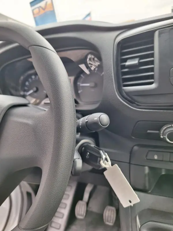 Vue intérieure centrée sur le volant et le tableau de bord noir de l'Opel Vivaro blanc, avec clé insérée dans le contact.