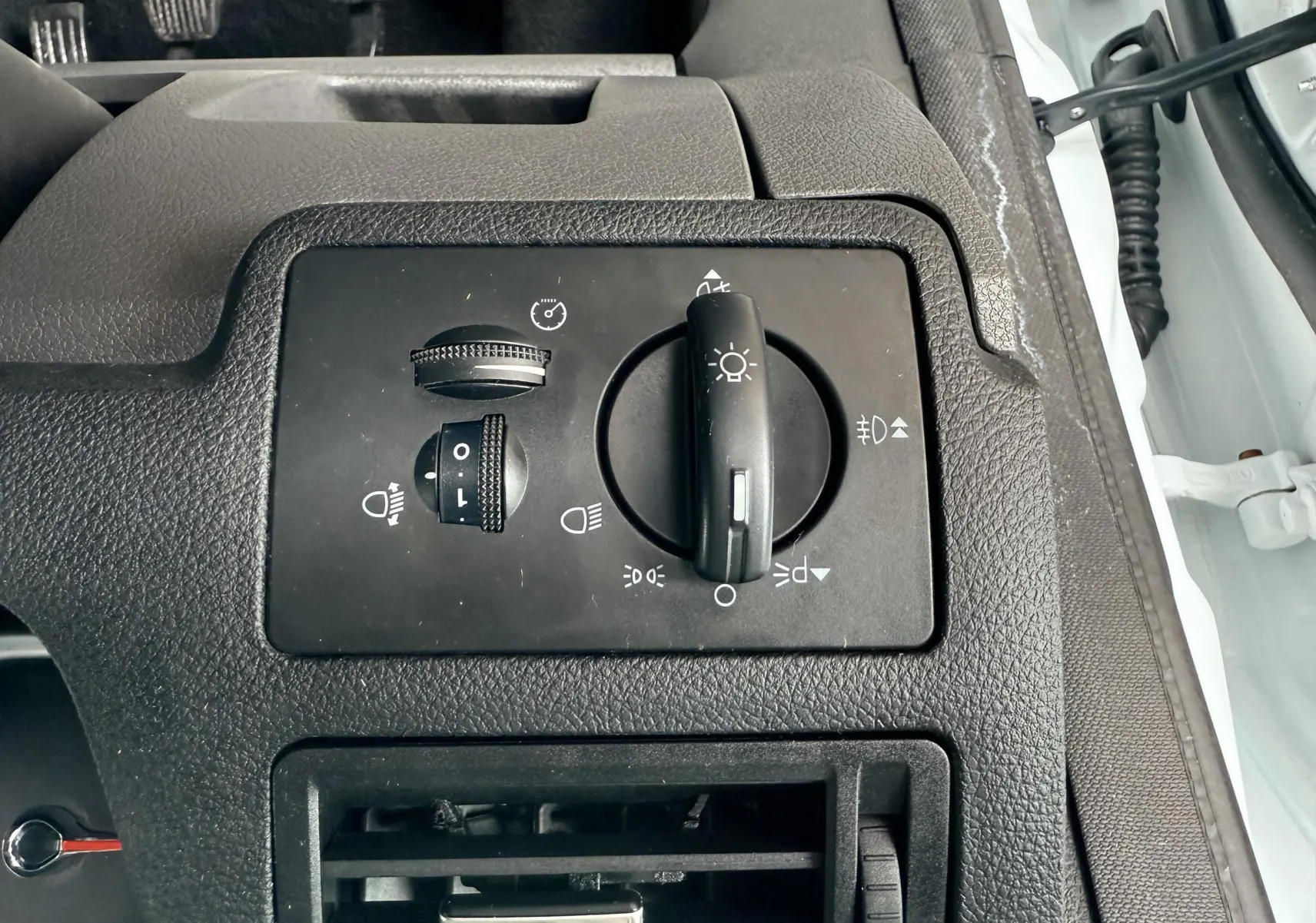 Gros plan sur les commandes d'éclairage et ventilation côté gauche intérieur d'un Ford Kuga blanc de 2012.