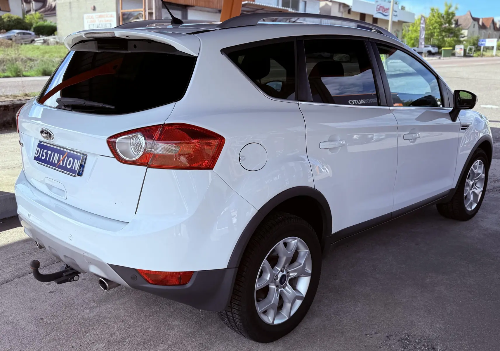 Vue 3/4 arrière droite d'un Ford Kuga blanc avec attelage et jantes alliage sous abri.