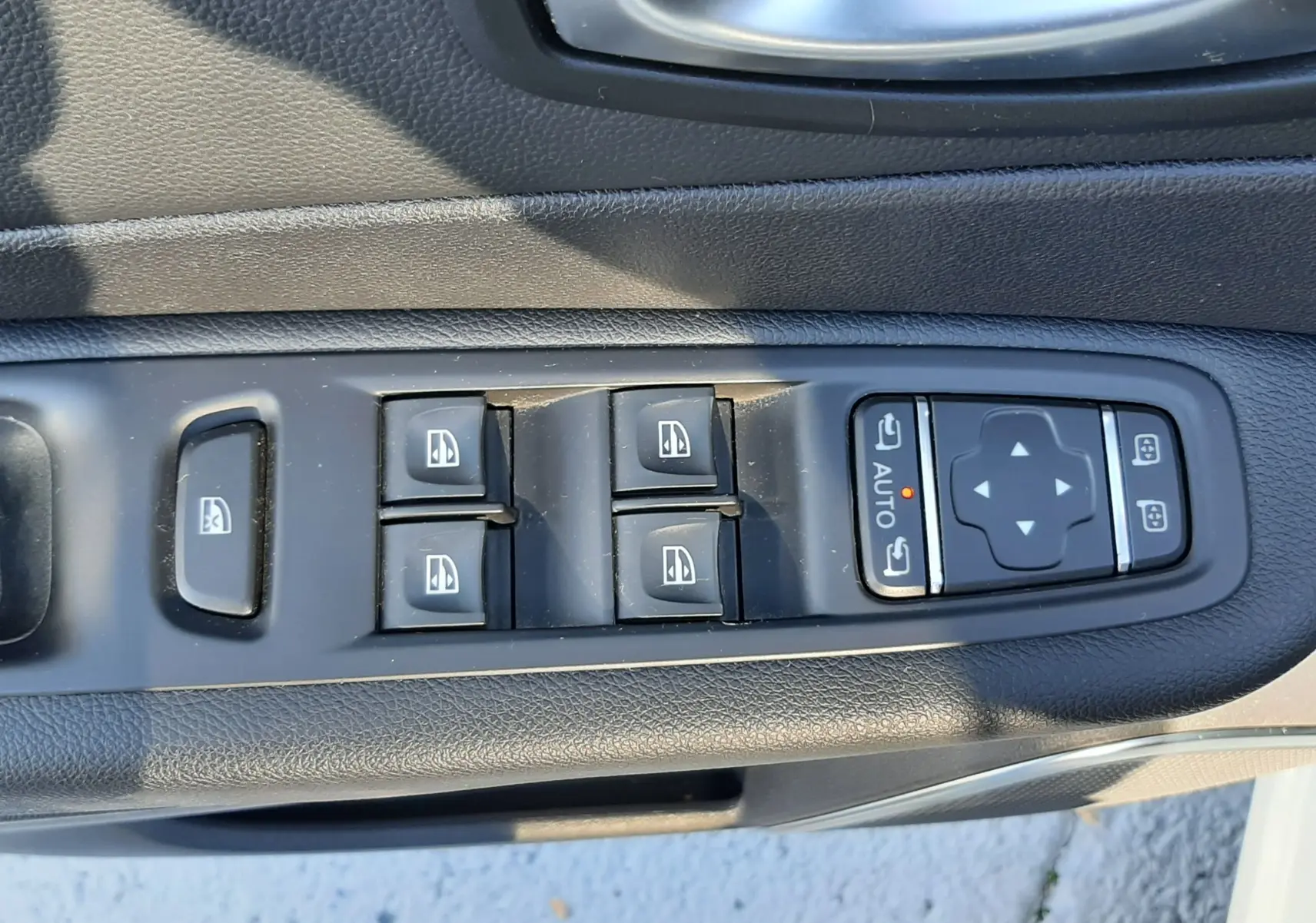 Gros plan sur les commandes de lève-vitres et réglages des rétroviseurs côté conducteur du Renault Captur blanc nacré.