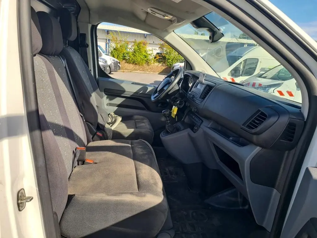 Intérieur du Peugeot Expert Fourgon blanc 2022 vu côté conducteur, montrant sièges et tableau de bord noir.