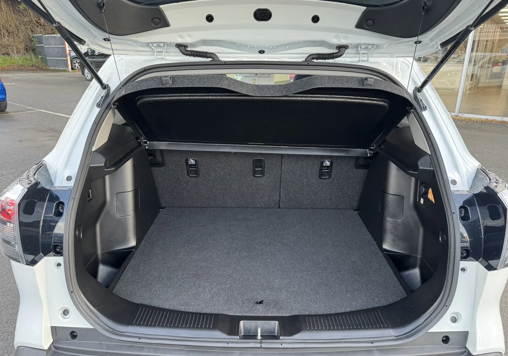 Coffre ouvert vu de l'arrière d'un Suzuki S-Cross blanc 2023, montrant un espace de chargement propre et spacieux.