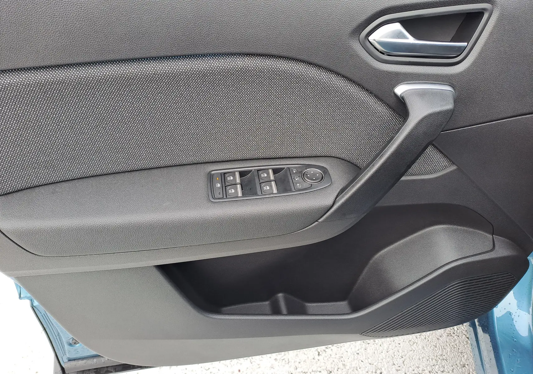 Vue rapprochée de la porte avant gauche de la Renault Symbioz bleu mercure, montrant la poignée et les commandes de vitres.