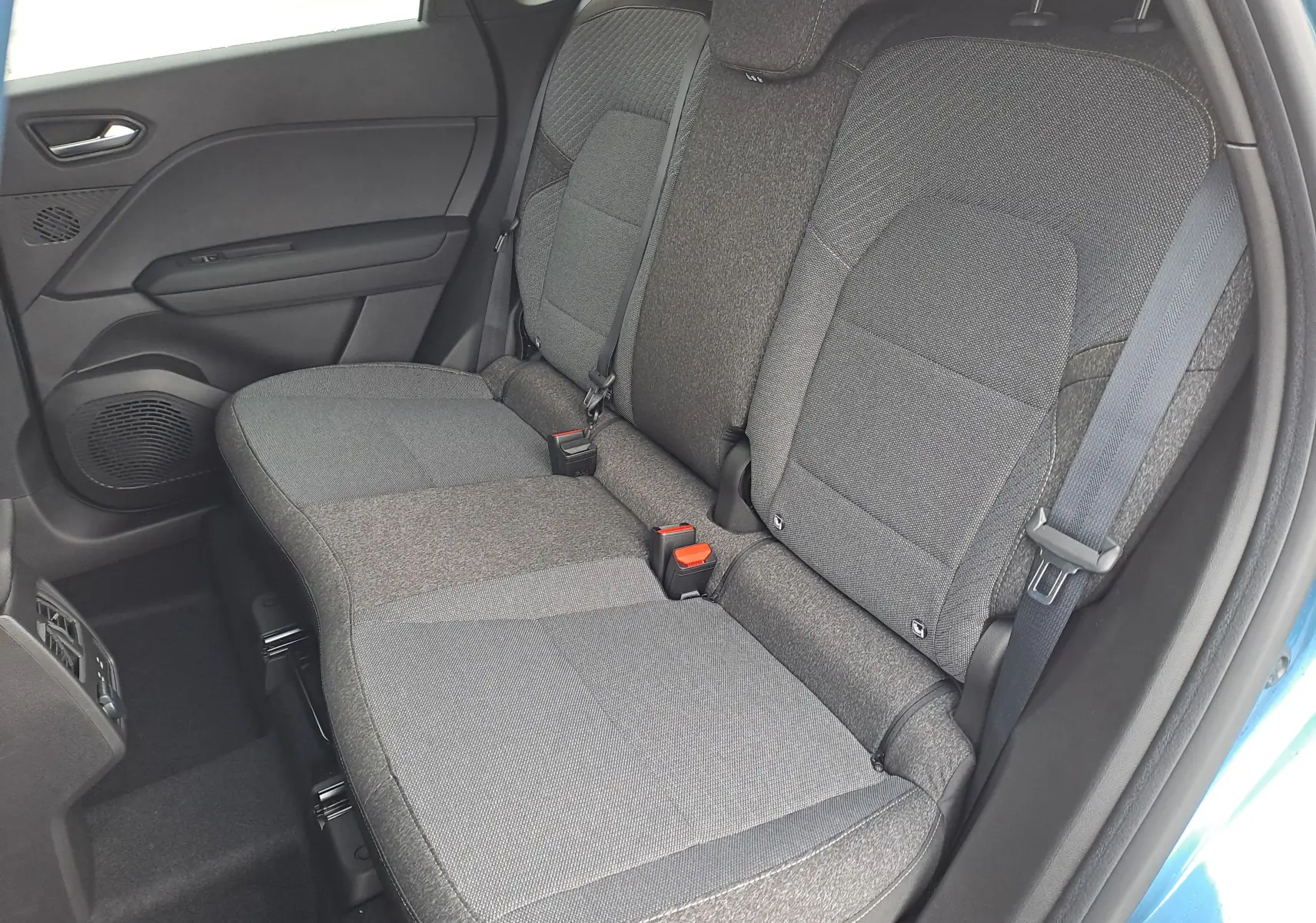 Vue latérale des sièges arrière gris foncé du Renault Symbioz 2025, avec ceinture de sécurité et porte bleu mercure partiellement visible.