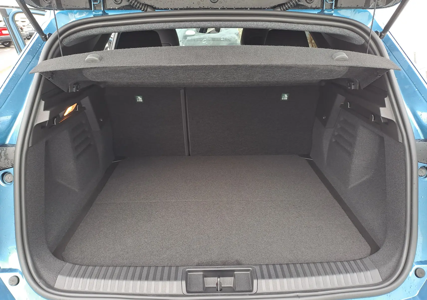 Coffre ouvert vu de l'arrière d'une Renault Symbioz bleu mercure, montrant un espace de chargement spacieux et propre.