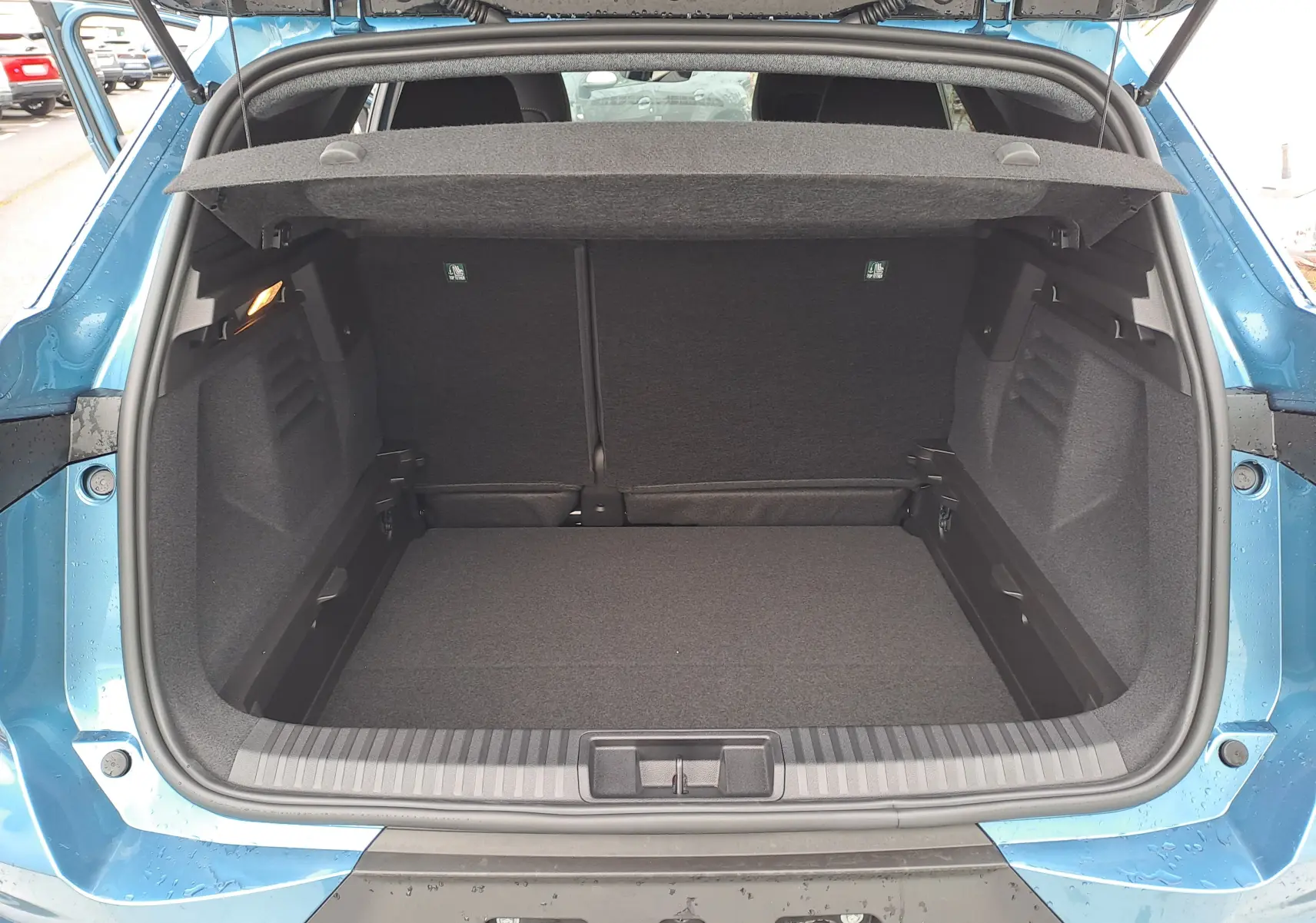 Coffre ouvert vu de l'arrière d'une Renault Symbioz bleu mercure, montrant un espace de chargement propre et spacieux.