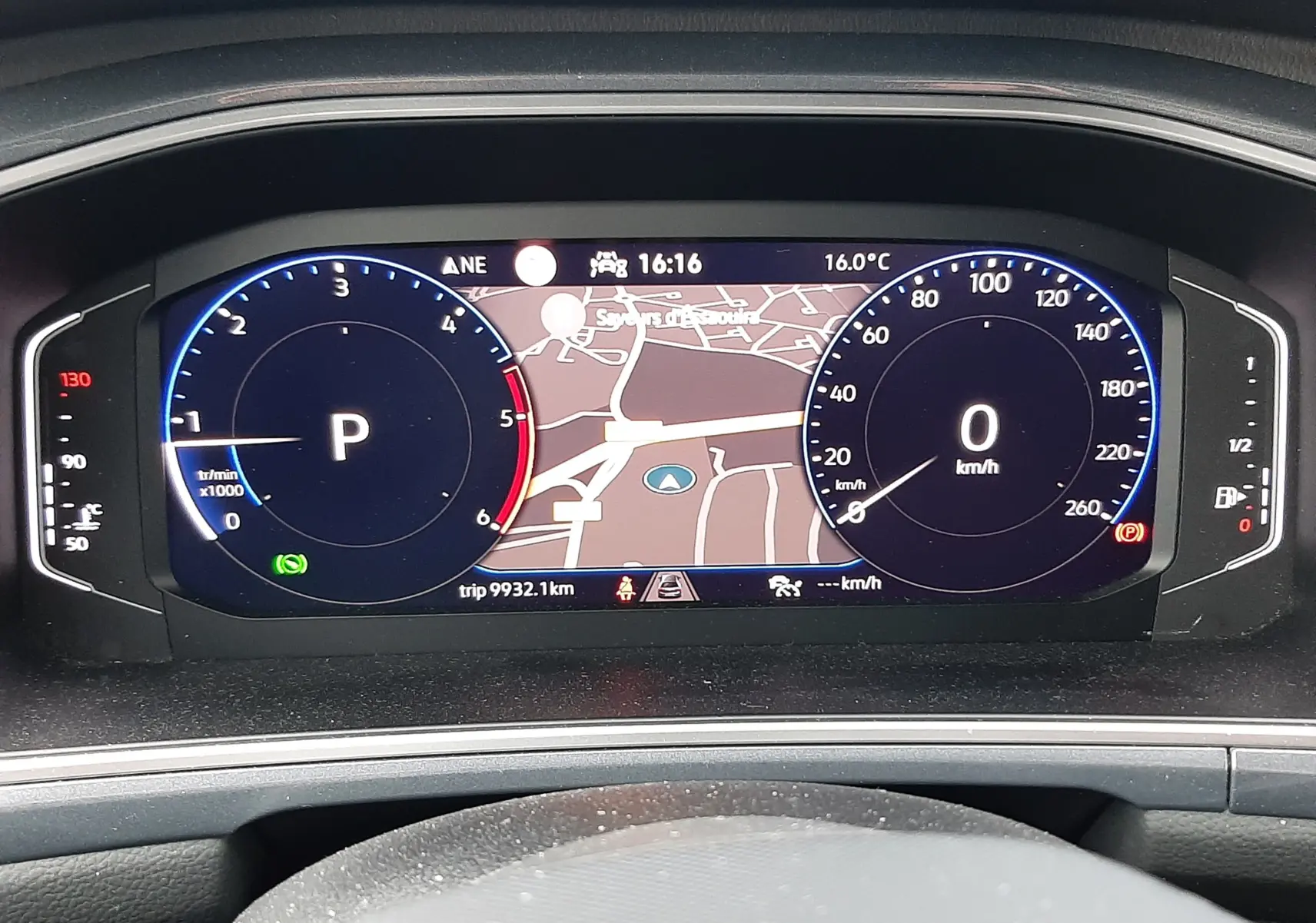 Tableau de bord numérique du Volkswagen T-Roc gris pyrite 2023, affichant la navigation et compteurs à l'arrêt.