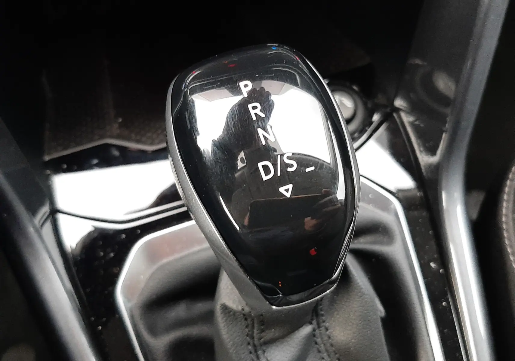 Le levier de vitesses automatique noir brillant du Volkswagen T-Roc 2023, vue rapprochée de la console centrale.