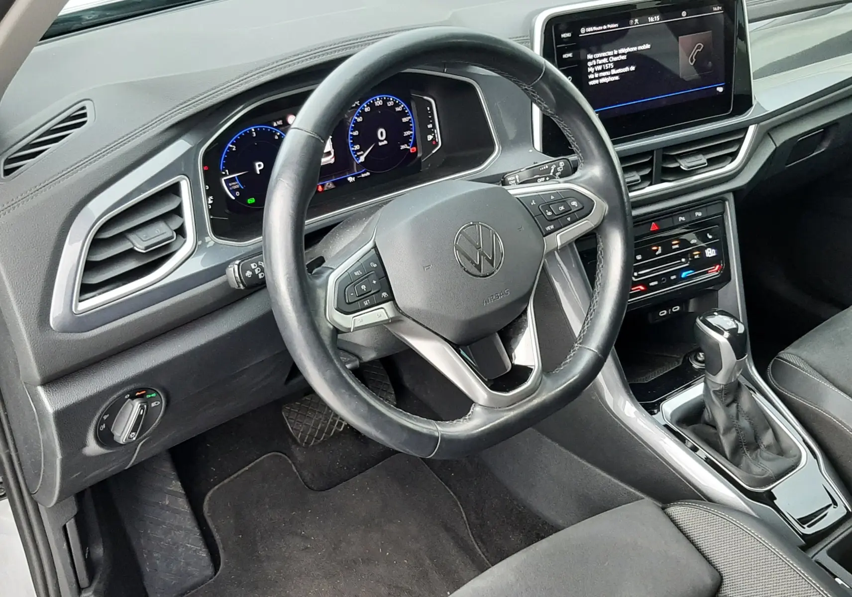 Vue intérieure du poste de conduite du Volkswagen T-Roc 2023, tableau de bord numérique et volant multifonction noir.