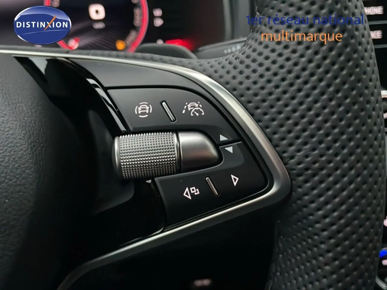 Gros plan sur les commandes au volant en cuir perforé noir du Skoda Karoq gris argent 2025, avec boutons multifonctions.